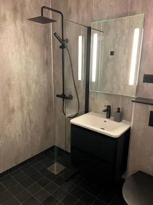 a bathroom with a sink and a shower and a mirror at Tunold Gård - Kårhus in Mindresunde