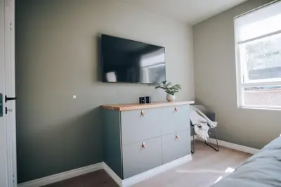 a bedroom with a dresser with a tv on the wall at Odda Apartments - 2BR & 3BR - Parking - T32 in Odda