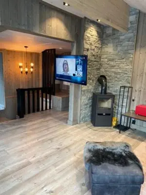 a living room with a tv in a stone wall at Villa Solsiden Geilo in Geilo