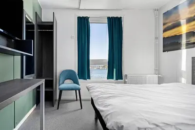 a bedroom with a bed and a chair and a window at Aiden by Best Western Trondheim Airport in Stjoerdal