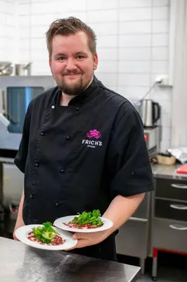 a man in a kitchen holding two plates of food at Dale-Gudbrands Gard by Frich`s in Sør-Fron