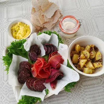a plate of food with sausage and potatoes and other foods at Glassigloo med panoramautsikt - Nordlys og stjernehimmel - Fosen in Husby