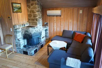 a living room with a couch and a stone fireplace at Melkevoll Bretun Camping in Briksdalsbre