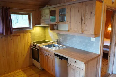 a kitchen with wooden cabinets and a sink at Melkevoll Bretun Camping in Briksdalsbre