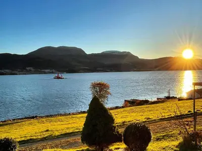a boat on a large lake with the sun setting at 5 person holiday home in averøy in Stokke