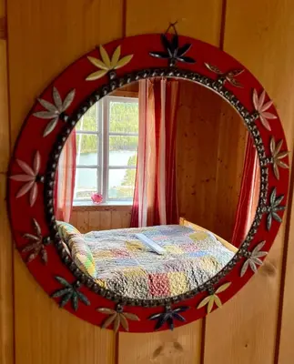 a mirror on a wall with a bed in a room at Reinheimen Lodge in Skjåk