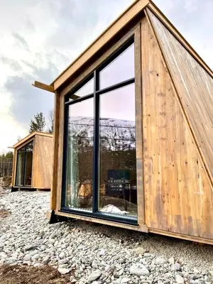 a small wooden house with a large window on a rocks at Reinheimen Lodge in Skjåk
