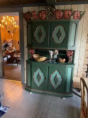 a green cabinet in a room with a table at Reinheimen Lodge in Skjåk
