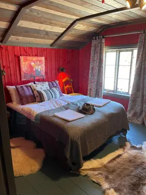 a large bed in a room with red walls at Reinheimen Lodge in Skjåk