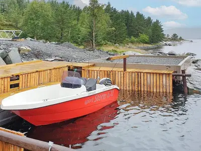a red and white boat sitting at a dock at 8 person holiday home in Svelgen in Svelgen