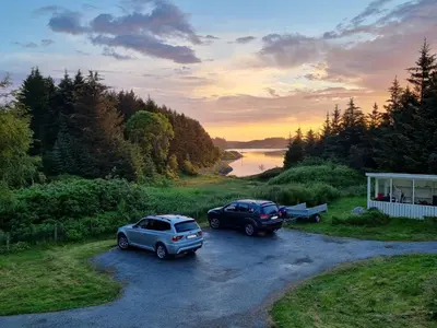 two cars parked in a parking lot next to a river at Vollvaagen Apartments Smøla, boat included in Smøla
