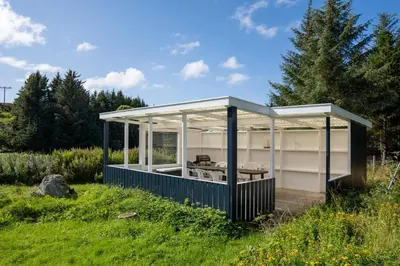 a house with a greenhouse in a field at Vollvaagen Apartments Smøla, boat included in Smøla