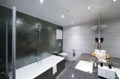 a bathroom with a tub and a shower and a toilet at Scandic Ørnen in Bergen