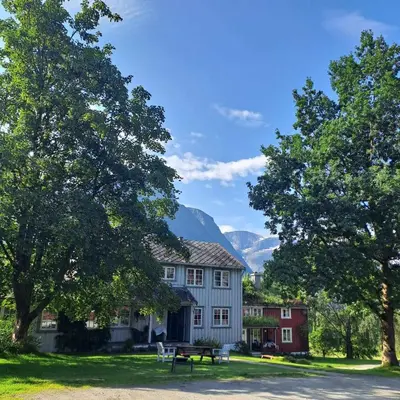 a house with a picnic table and mountains in the background at Lensmansgarden in Innfjorden