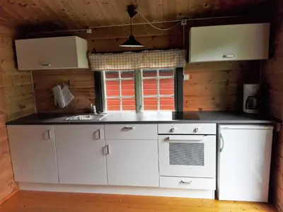 a kitchen with white cabinets and a sink at Lensmansgarden in Innfjorden