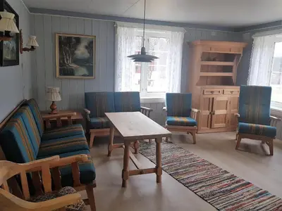 a living room with a table and blue chairs at Lensmansgarden Marteinsgarden in Innfjorden