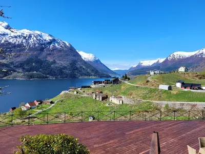 a village on a hill with a lake and mountains at Flohytta in Stryn