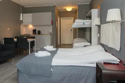 a bedroom with a large bed and a kitchen at Oppdal Gjestetun Hotell in Oppdal