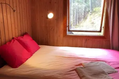 a bed in a room with a red pillow and a window at Cottage - Sleeps 6 - Parking - Patio in Ytteroy