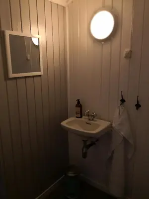 a bathroom with a sink and a light on the wall at Yttervik gard in Steinkjer