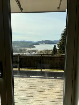 a door to a balcony with a view of a lake at Høgli på Yttervik gard in Fosnesstranden