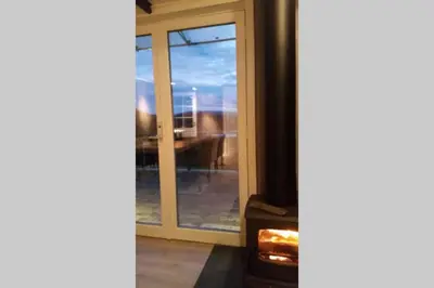 a glass door with a stove in a room at Høgli på Yttervik gard in Fosnesstranden