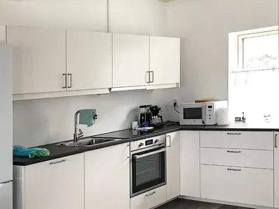 a kitchen with white cabinets and a sink and a microwave at 6 person holiday home in Kverva in Dyrvik