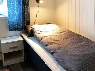 a small bedroom with a bed and a nightstand at 6 person holiday home in Kverva in Dyrvik