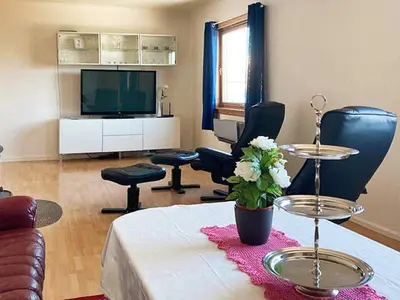 a living room with a table and chairs and a television at 9 person holiday home in KORTGARDEN in Skalle