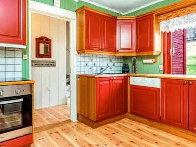 a kitchen with red cabinets and wooden floors at 9 person holiday home in KORTGARDEN in Skalle