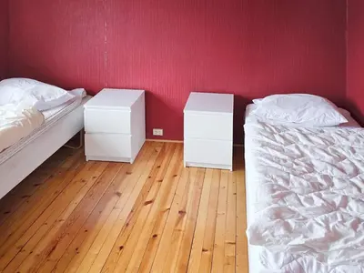 two beds in a room with red walls and wooden floors at 9 person holiday home in KORTGARDEN in Skalle