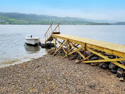 a boat is docked next to a wooden pier at 9 person holiday home in KORTGARDEN in Skalle