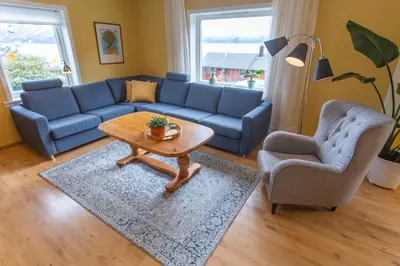 a living room with a blue couch and a table and chairs at Raaehuset in Lavik
