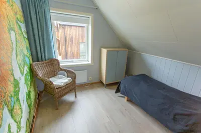 a bedroom with a bed and a chair and a window at Raaehuset in Lavik