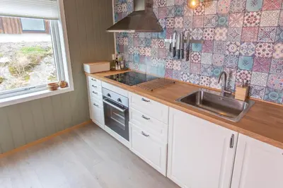 a kitchen with white cabinets and a sink and a window at Raaehuset in Lavik