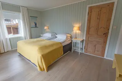 a bedroom with a bed and a door with two lamps at Raaehuset in Lavik