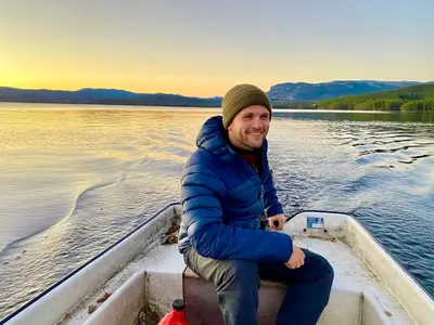 a man sitting on the back of a boat on the water at Bolkesjø Gaard in Notodden