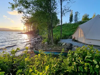 a tent and a canoe on the shore of a lake at Bolkesjø Gaard in Notodden