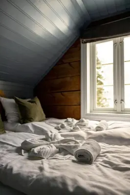 a bed with towels on it with a window at Vollsnes Gjestehus in Stryn