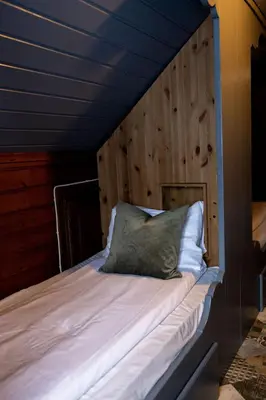 a bed in a room with a wooden wall at Vollsnes Gjestehus in Stryn