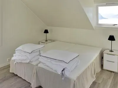 a bedroom with a bed with white sheets and a window at 10 person holiday home in Stordal in Stordal