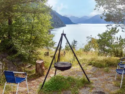 a fire pit and chairs next to a lake at 10 person holiday home in Stordal in Stordal