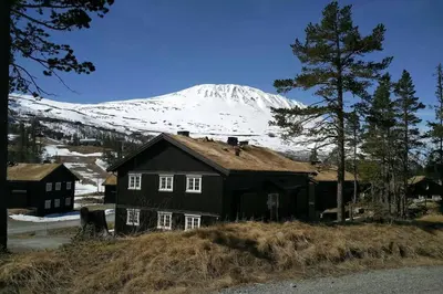 a black house with a snow covered mountain in the background at Apartment Gaustablikk in Gaustablikk