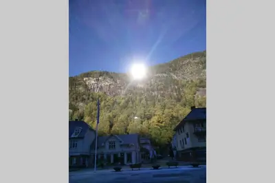 a sun is shining on a mountain with houses at Apartment Gaustablikk in Gaustablikk