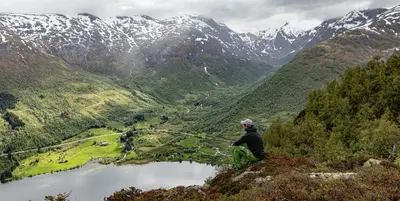 a man sitting on top of a mountain overlooking a valley at Hodlekve Panorama 5 - amazing view in Sogndal