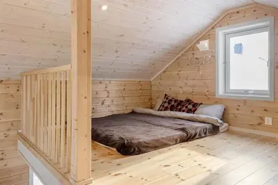 a bed in a log cabin with a window at Tiny mountain cabin with a panoramic view in Giljane
