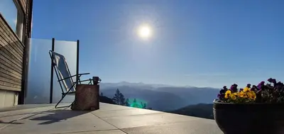 a view of the mountains from a balcony with flowers at Tiny mountain cabin with a panoramic view in Giljane