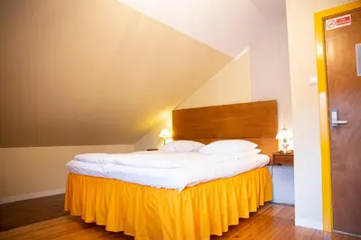 a bedroom with a large bed with a yellow skirt at Tiglkåk in Åndalsnes