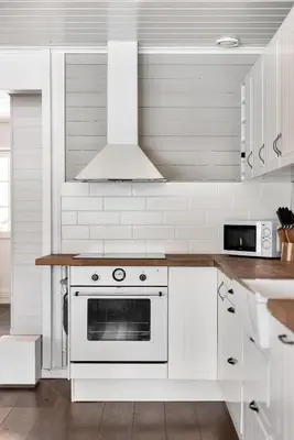 a white kitchen with a stove and a microwave at Cabin in Trysil with seaview to lake in Trysil