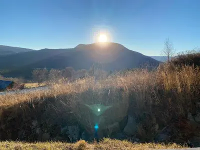 a sun setting over a hill with a field of grass at Private apartments!Oppdal Alpintun, Skisenter-Stølen in Oppdal